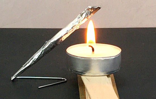 Rocket on a paperclip launcher. The tip of the rocket is being heated by the flame of a candle.