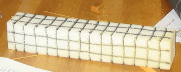 A rectangular prism made of foam has grid lines drawn on each side