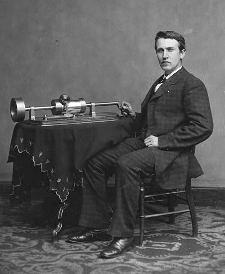 Black and white photo of Thomas Edison seated with a phonograph