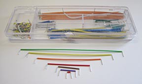 Jumper wires of different sizes and colors laid on a table and in a plastic wire organizer