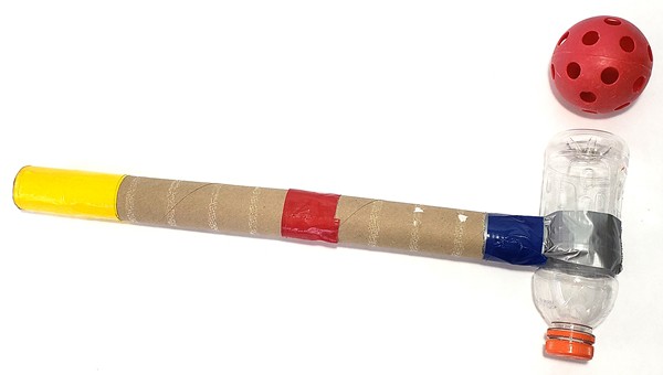 Two paper towel tubes duct taped to a plastic bottle to form a  mallet, next to a whiffle ball. 