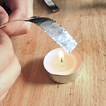 Piece of aluminum foil curling from the heat of a flame