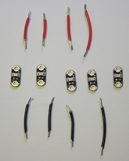 Four red wires and four black wires next to five LEDs
