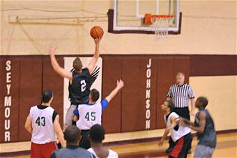 A player shoots a basketball towards the basket from the baseline