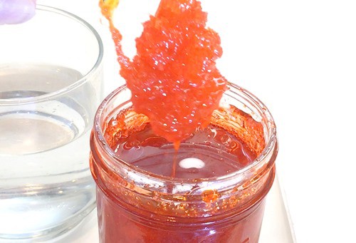 Rock candy being pulled up from a jar with a thick syrup. 