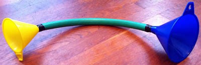 Two plastic funnels are inserted into the ends of a segment of garden hose and secured with tape