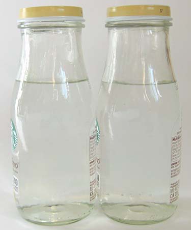 Two glass bottles filled with water are placed side-by-side so that the walls of each bottle touch