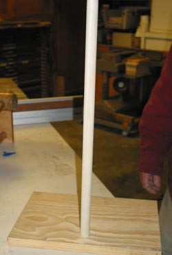 A wooden dowel is inserted vertically in the center of a wooden block