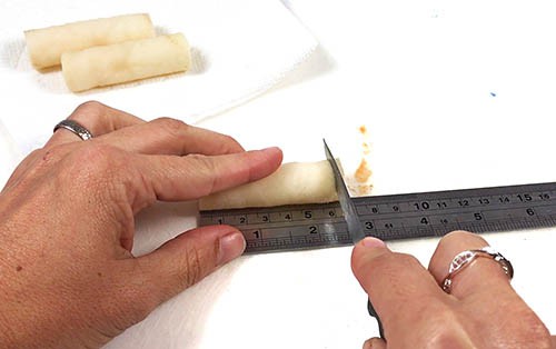 The potato strips are measured and cut to the same length.