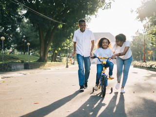 Child riding bike with parents