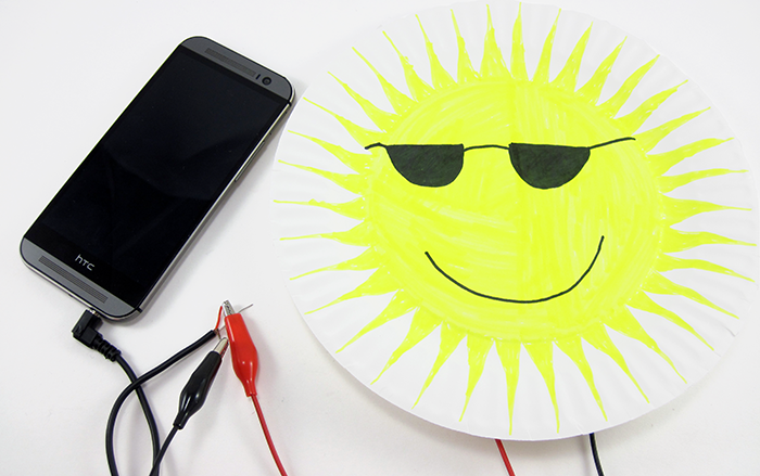 A decorated paper speaker connected to the audio jack of a smartphone
