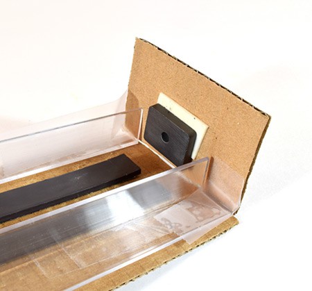 A rectangular magnet is taped to a piece of cardboard and secured perpendicularly to the end of the track