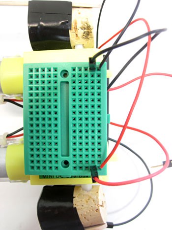 Wires from a battery pack and DC motor are connected to a mini breadboard