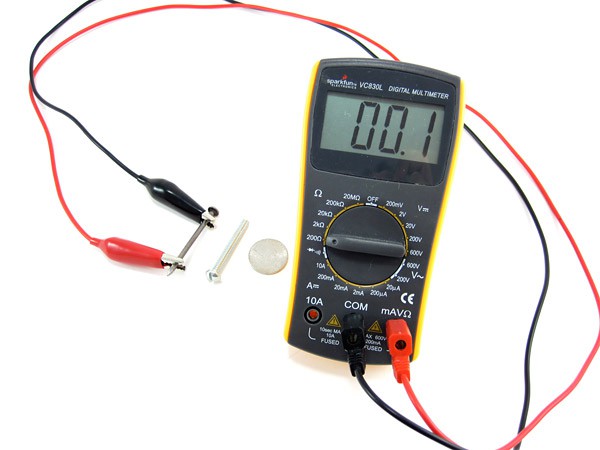 A multimeter with alligator clip leads attached to a nail