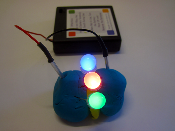 Electric play dough example with three LEDs lit up forming a squishy circuit from insulating and conductive dough