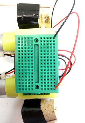 Wires from a battery pack are connected to a mini breadboard