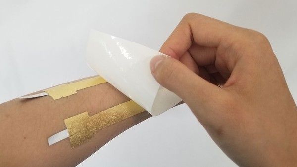 Peeling off the temporary tattoo backing after it is wet. 