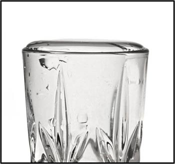 Water in a glass cup raises above the rim without spilling