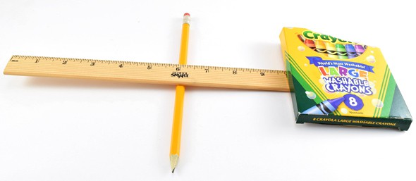 A box of crayons rests on one side of a ruler that is supported in the center by a pencil