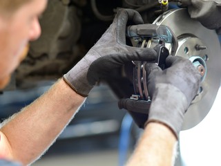 Car mechanic repairs breakes from vehicle in a workshop