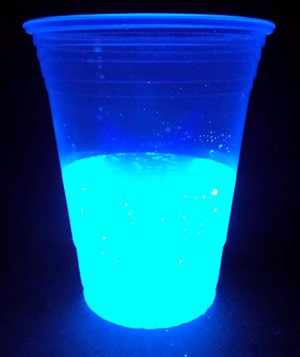 Tonic water in a cup glows fluorescent blue under a black light