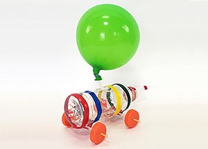 A car with a plastic bottle for a body, skewers and bottle caps for axles and wheels, and a balloon for propulsion.
