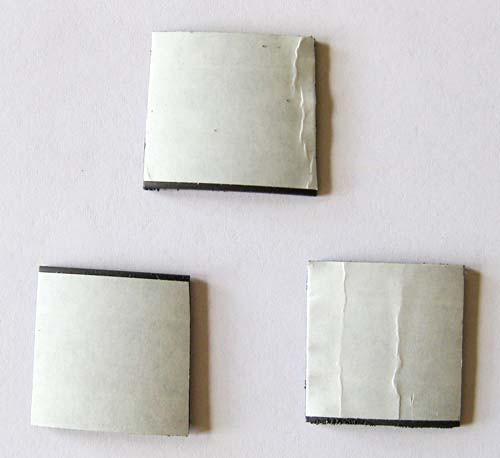 Three squares of adhesive magnetic tape