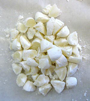Several Mentos mint candies are cut into small pieces on wax paper