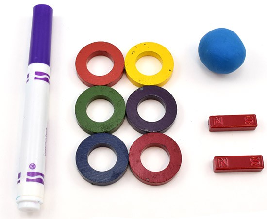 A marker, six magnetic rings, two bar magnets, and a ball of putty
