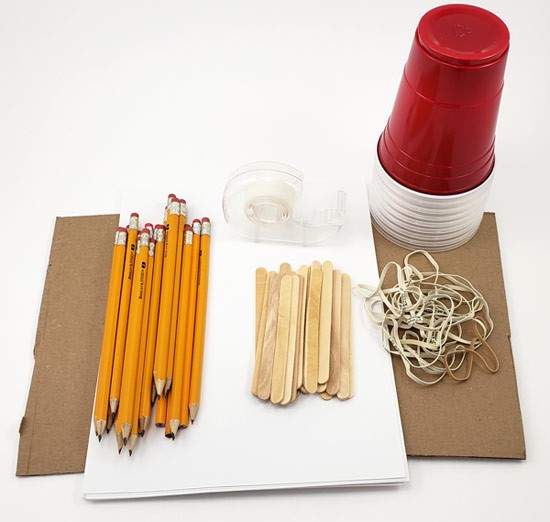 Cardboard, pencils, popsicle sticks, tape, paper, rubber bands and a stack of plastic cups