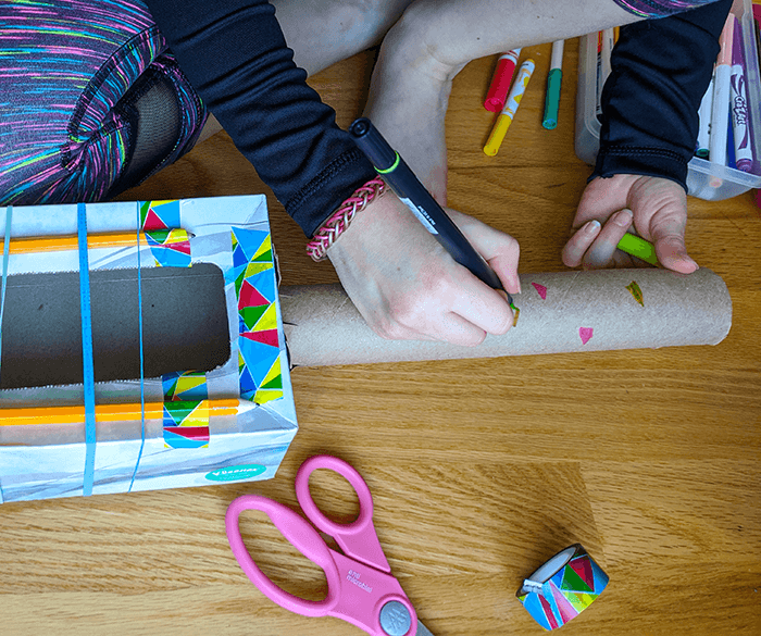 Student using markers and craft supplies to decorate a rubber band guitar