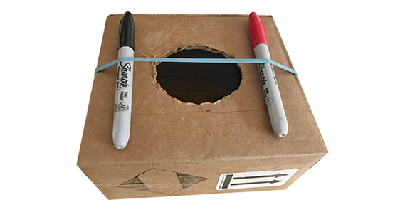 Cardboard box with markers and rubber bands for a simple guitar