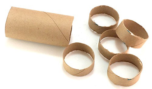 A longer section of cardboard tube with 5 shorter sections placed next to it. 