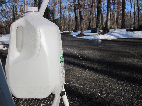 A milk jug filled with water with two small holes, allowing small streams of water to come out