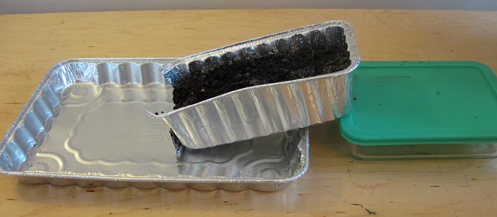Aluminum bread pan filled with soil is placed on an incline