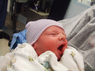 Newborn delivered by cesarean birth being held by father in operating room. 