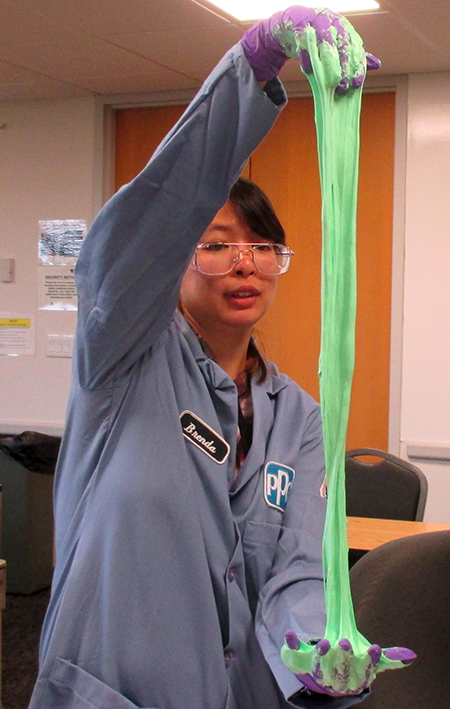 A PPG Industries volunteer stretches slime between her hands