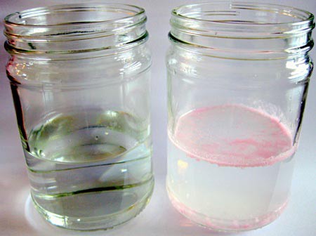A glass jar filled with water next to a glass jar filled with a mix of water and pink powder