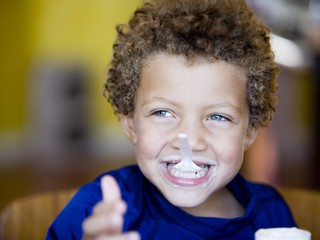 little boy with spoonful of yougt in his mouth