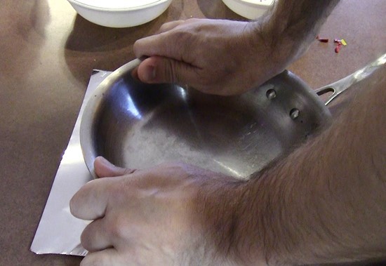 Frying pan pressed down on top of the aluminum foil. 