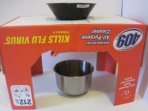 A bowl is placed beneath a funnel that is inserted into a hole cut in the top of a cardboard box