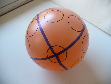 An orange balloon map stretched out with circles and latitude/longitude lines drawn on it.