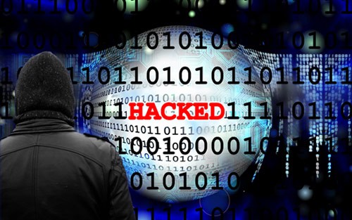 Image of a hooded figure looking at lines of binary code with the word 'hacked' highlighted in red