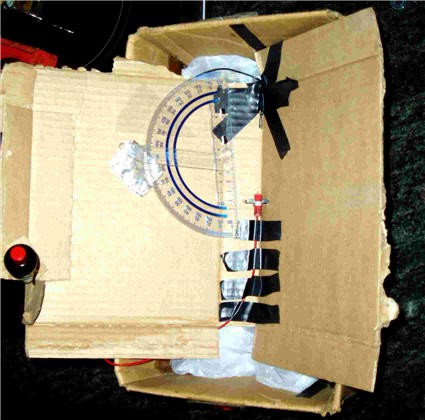 Cardboard is folded in half and a ruler and electrodes are taped to the inside near the crease