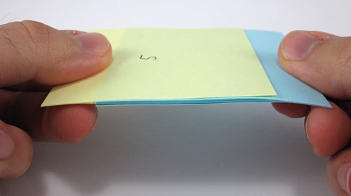 Two pads of blue and yellow paper with the paper from both interlaced