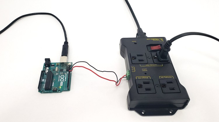 The IoT relay connected to an Arduino UNO with two jumper wires. An off-screen appliance is plugged in to the IoT relay.