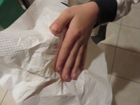 Someone wiping their hands with an unfolded paper towel