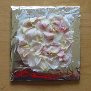 Flower petals are arranged over a layer of vegetable shortening that has been spread over a square of aluminum foil