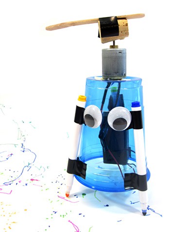 An assembled art bot made from a plastic cup, motor, markers, tape, cork and googly eyes