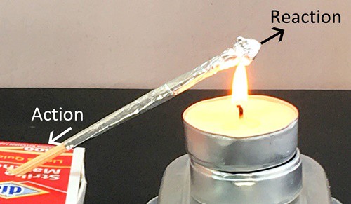 Matchstick rocket being launched. An arrow pointing up and away from the point of the rocket is labeled 'Reaction'. An arrow pointing the opposite direction starts at the bottom of the rocket and is labeled 'action'.